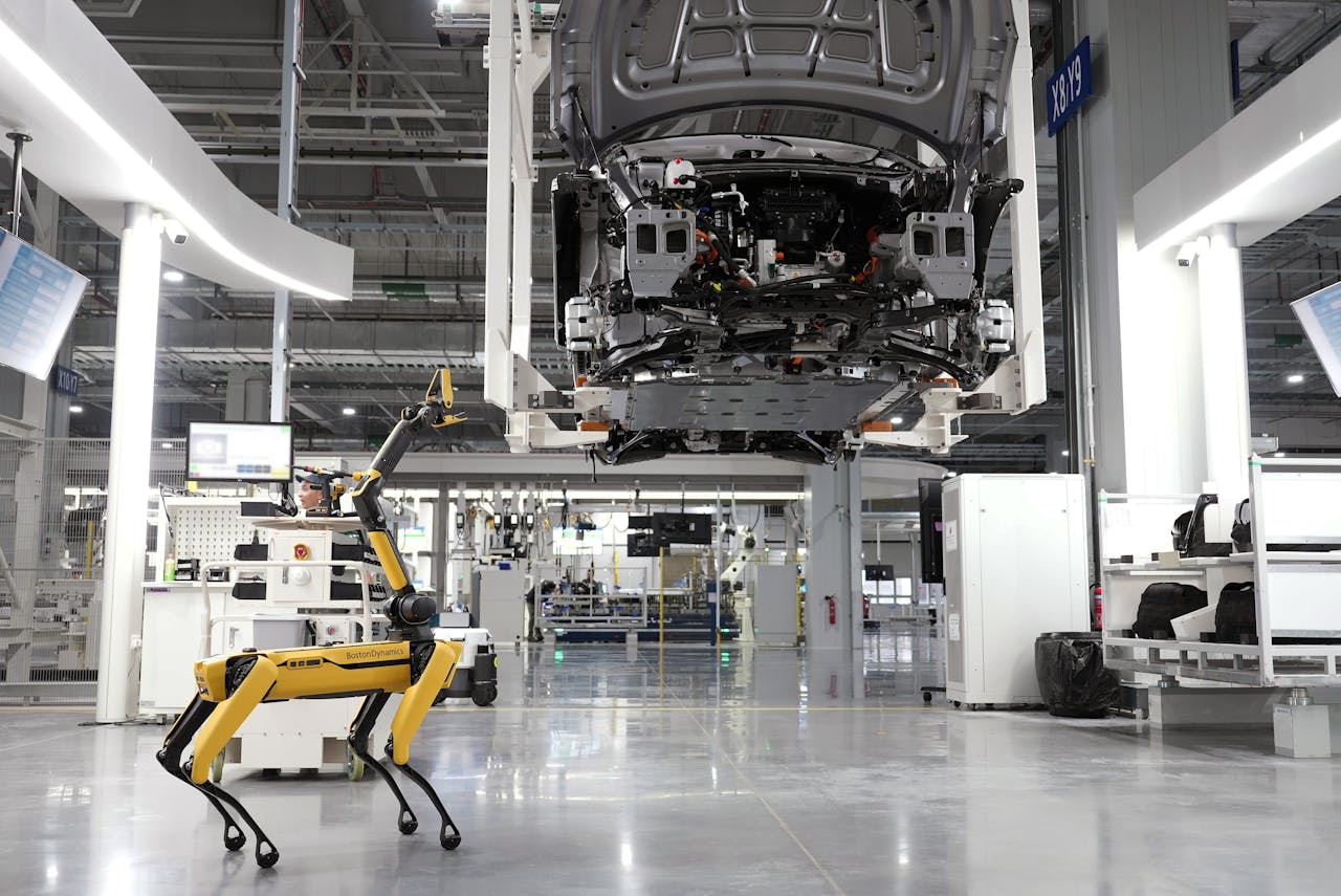 services-01 A robotic dog oversees an automated car assembly in a high-tech factory setting.